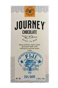 A large size packaged Journey Chocolate bar in an off-white cardboard box with wavy US postal service lines across the top, lower sides and bottom of the box. A gold foil postage stamp style seal with a cacao pod in the middle seals the box, with the word “Limited” in cursive in wavy concentric circles around the image and the word “Release” at the bottom. The Journey Chocolate logo is centered on the bar and a Fiji 70% dark stamp centered on the bottom, net weight 2.47 oz or 70 grams.