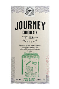 A large size packaged Journey Chocolate bar in an off-white cardboard box with wavy US postal service lines across the top, lower sides and bottom of the box. A white postage stamp style seal with a cacao pod in the middle seals the box, with the words "Experts in small-batch, craft chocolate" in a circle around the image and the words "Seal of Quality" at the bottom. The Journey Chocolate logo is centered on the bar and an Madagascar 70% dark stamp centered on the bottom, net weight 2.47 oz or 70 grams