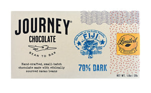 A medium size packaged Journey Chocolate bar in an off-white cardboard box with wavy US postal service lines across the top and right sides of the box. A gold foil postage stamp style seal with a cacao pod in the middle seals the box, with the word “Limited” in cursive in wavy concentric circles around the image and the word “Release” at the bottom. The journey chocolate logo is on the left side of the  bar and a Fiji 70% dark stamp centered in the middle, net weight 1.0 oz or 28 grams.